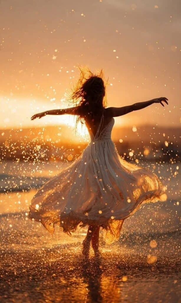 Femme qui danse joyeusement sur la plage au soleil couchant.