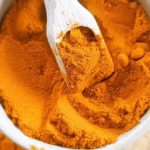 Curcuma moulu du Sri Lanka dans un pot en terre et cuillers en bois sur planche en bois