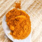 Curcuma moulu du Sri Lanka sur une cuiller en bois et planche en bois