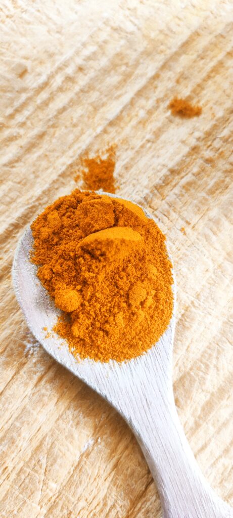Curcuma moulu du Sri Lanka sur une cuiller en bois et planche en bois