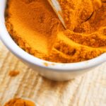 Curcuma moulu du Sri Lanka dans un pot en terre et cuillers en bois sur planche en bois