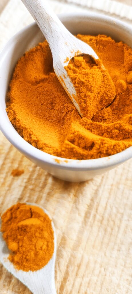 Curcuma moulu du Sri Lanka dans un pot en terre et cuillers en bois sur planche en bois